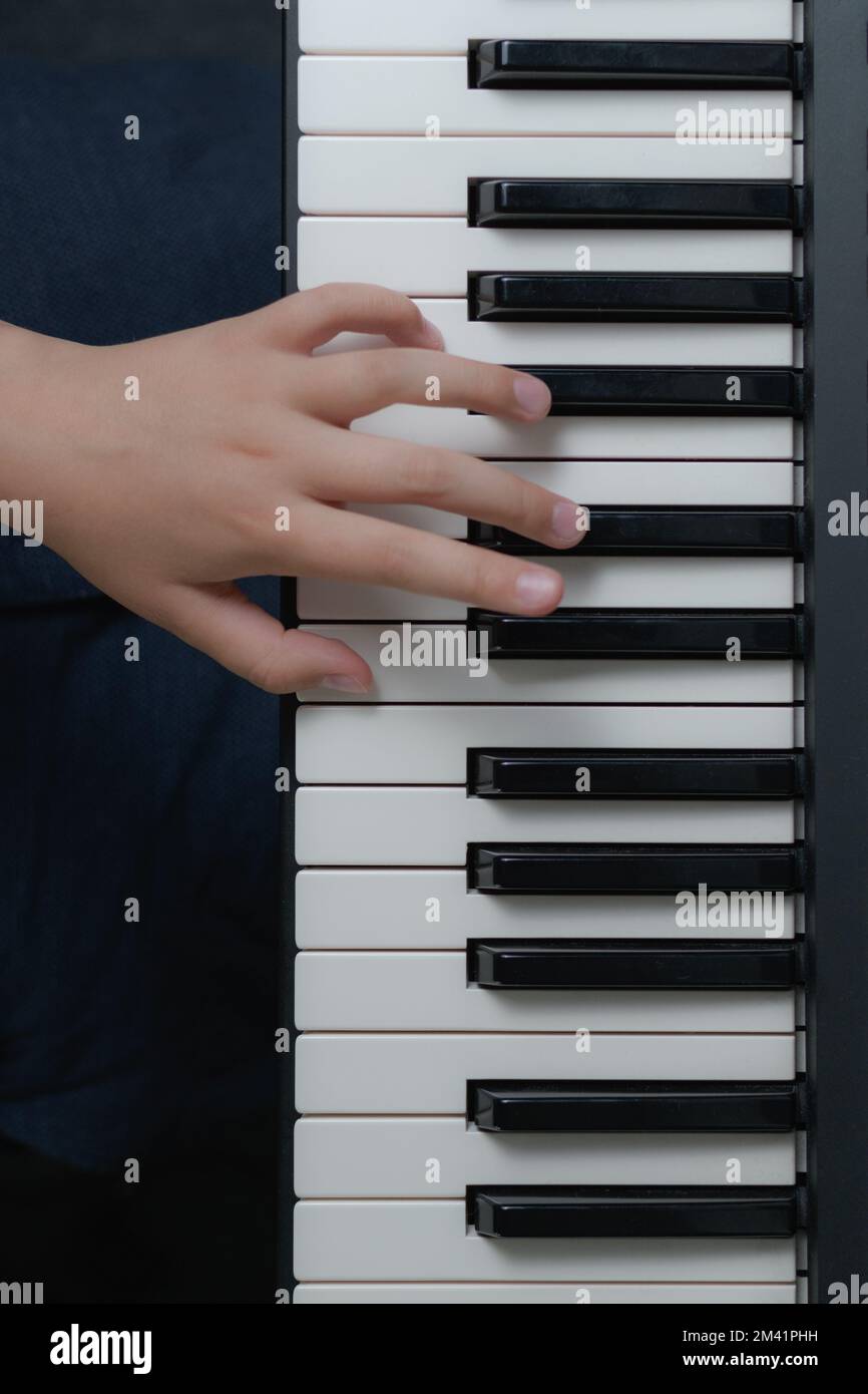 Doigts d'un enfant sur le clavier du piano. Format vertical. vue de dessus Banque D'Images