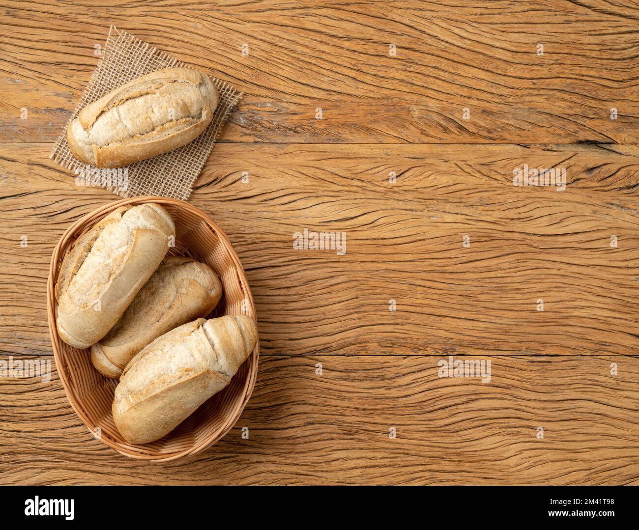 Pain français à grains entiers, pain salé ou pistolet dans un panier sur table en bois avec espace de copie. Banque D'Images