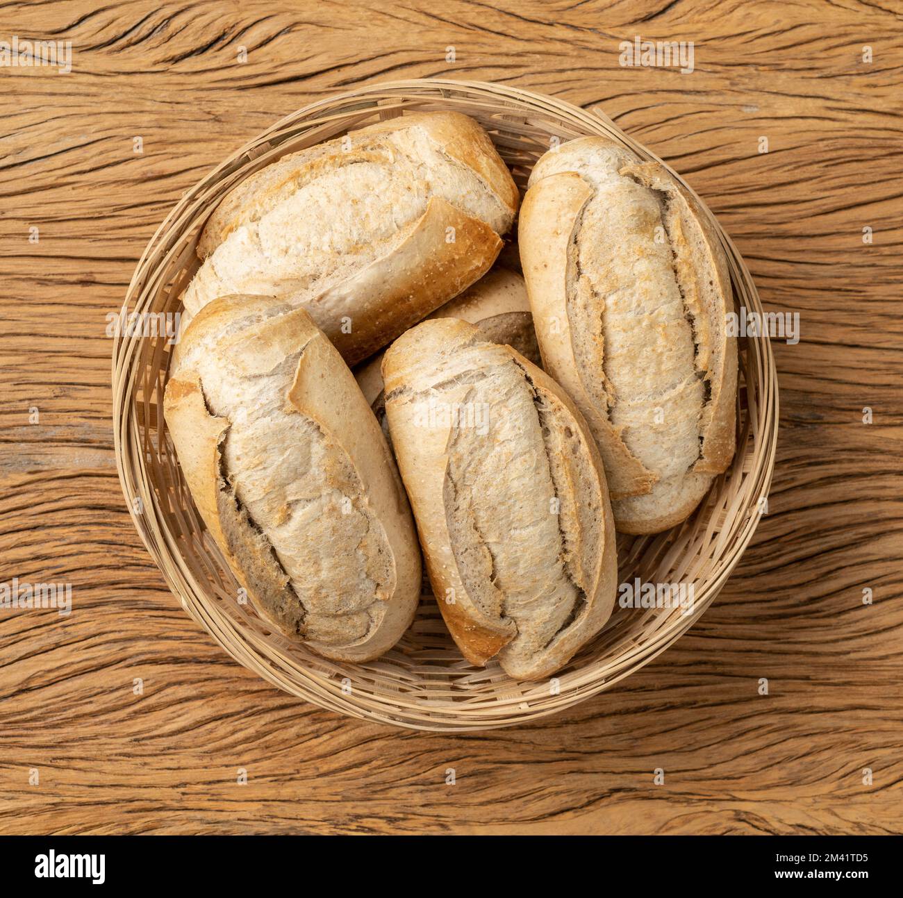 Pain français à grains entiers, pain salé ou pistolet dans un panier sur table en bois. Banque D'Images