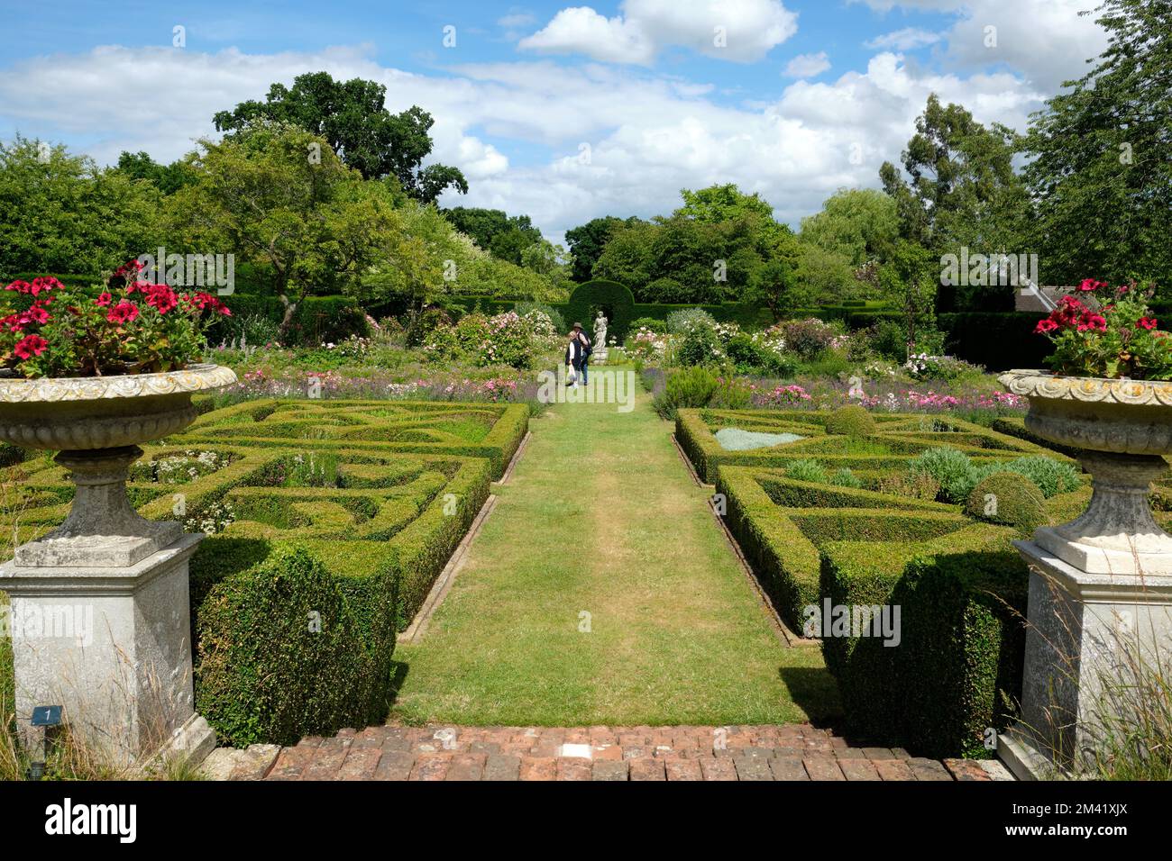 Entrée au jardin du parterre flanquée d'urnes en pierre en été avec ciel bleu et figures vue sur le paysage Banque D'Images