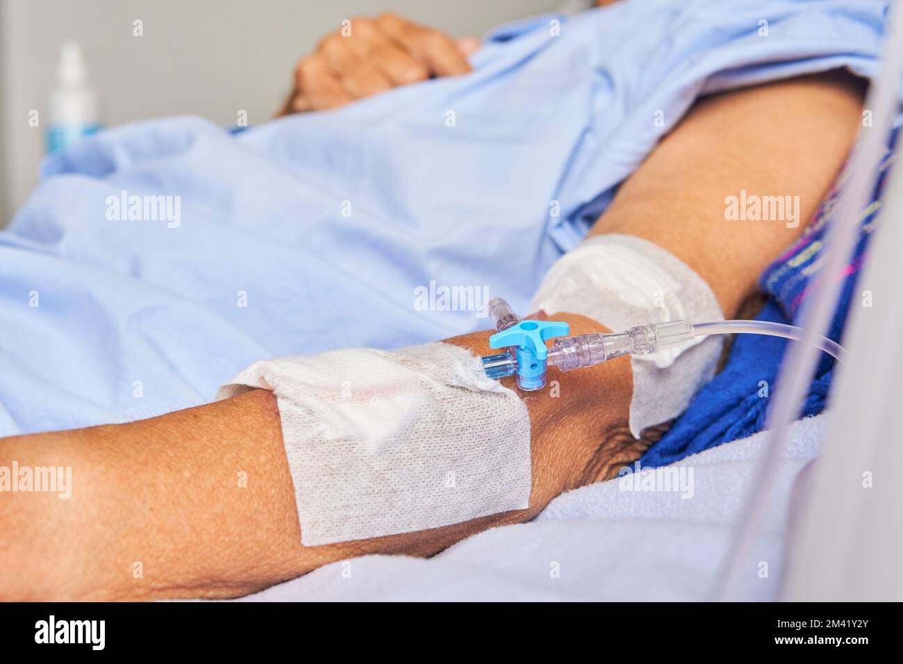 détail du bras de la femme âgée avec une ligne intraveineuse sur la civière dans la chambre d'hôpital Banque D'Images