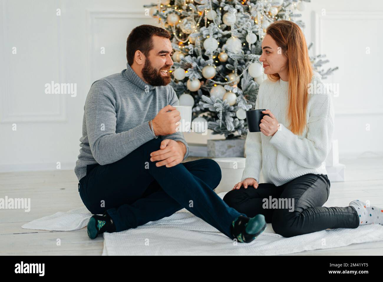 Un couple attrayant près de l'arbre de Noël et embrassant. Atmosphère du nouvel an. Câlins tendre près de l'arbre de Noël de deux personnes Banque D'Images