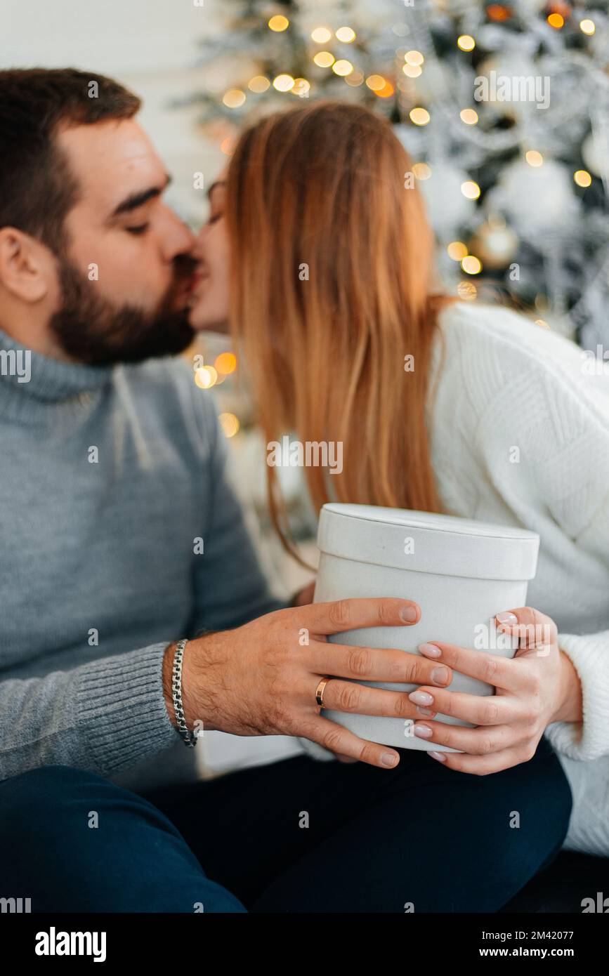 couple heureux près des boîtes-cadeaux et de l'arbre de noël. couple embrassant et regardant l'un l'autre près de l'arbre de noël. Banque D'Images