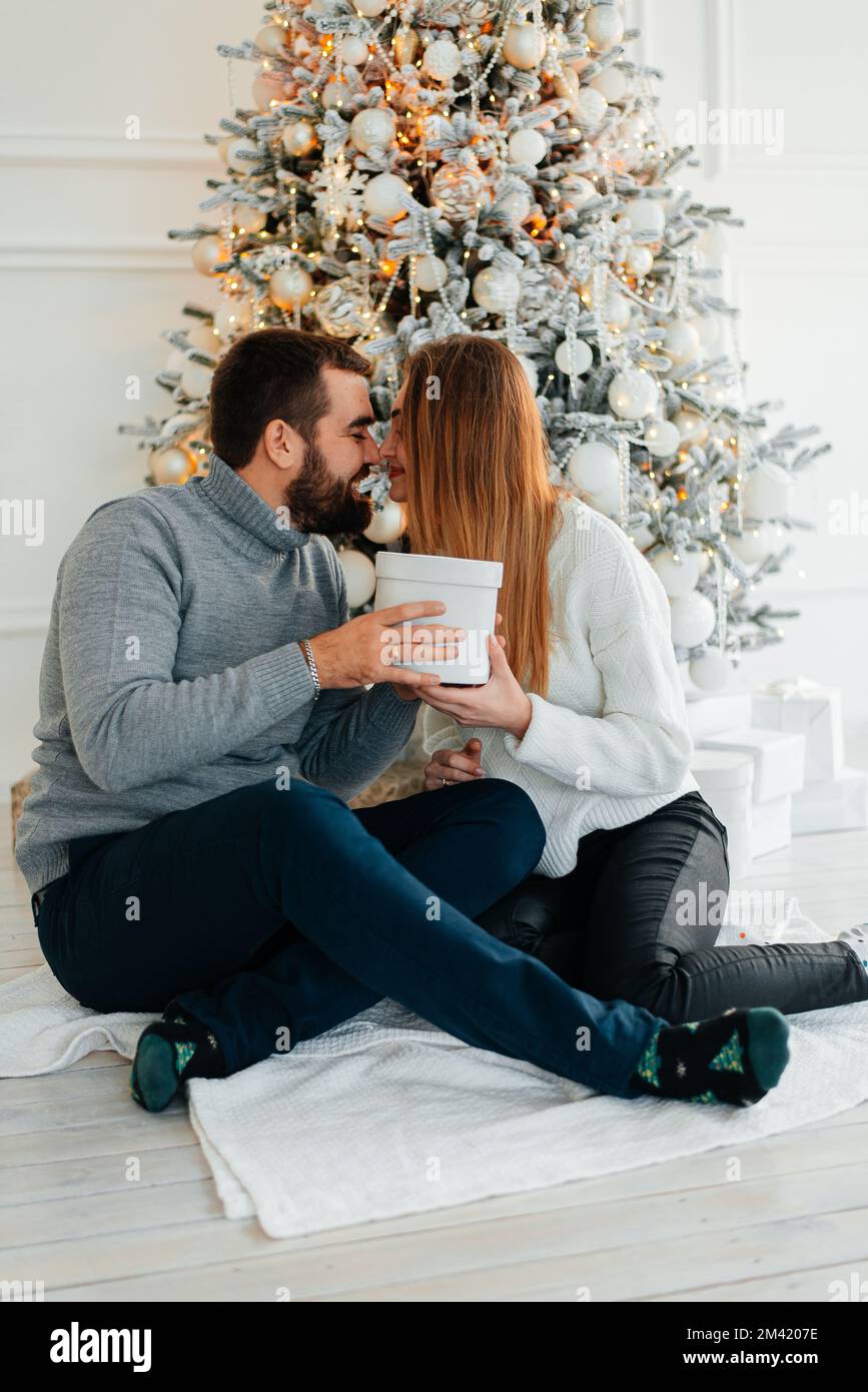 couple heureux près des boîtes-cadeaux et de l'arbre de noël. couple embrassant et regardant l'un l'autre près de l'arbre de noël. Banque D'Images