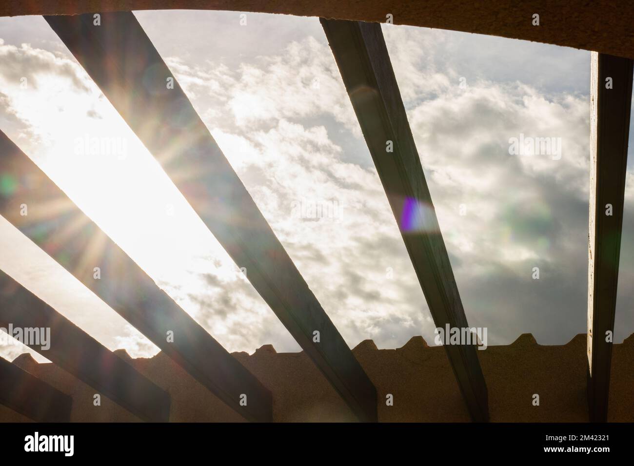 vue sur le ciel et le soleil à travers les poutres sur le toit Banque D'Images