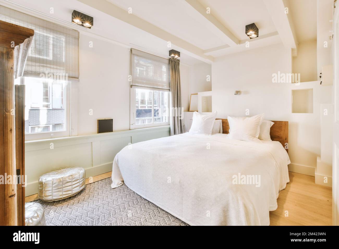 un lit dans une chambre avec parquet et draps blancs sur le cheveu Banque D'Images