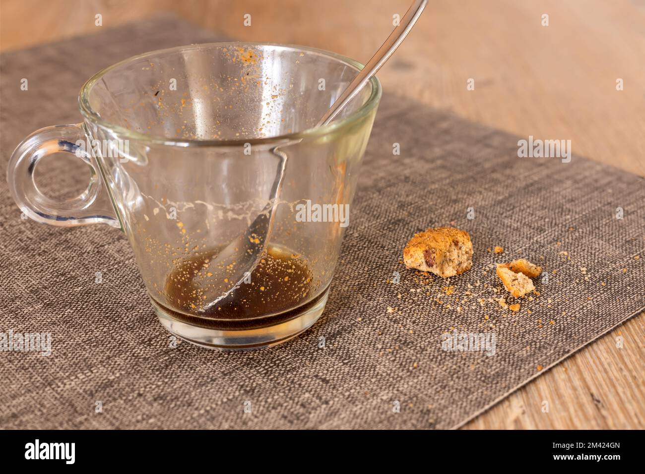 table en gros plan souillée de chapelure de biscuits après le petit déjeuner et de tasse de café en verre sale Banque D'Images