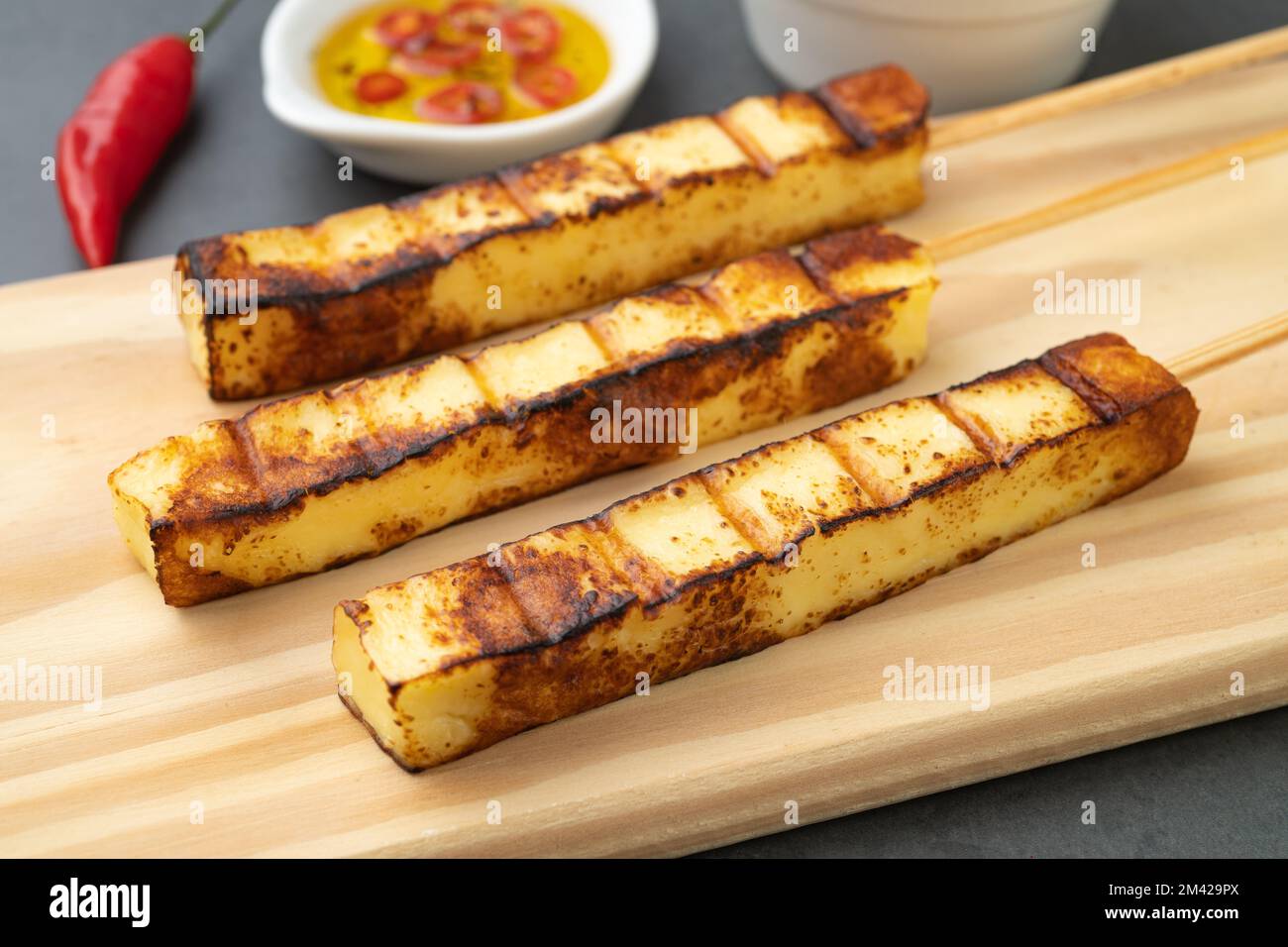 Le Rennet grillé ou le Coalho sur une planche de bois avec du sirop de sucre et du poivre. Banque D'Images