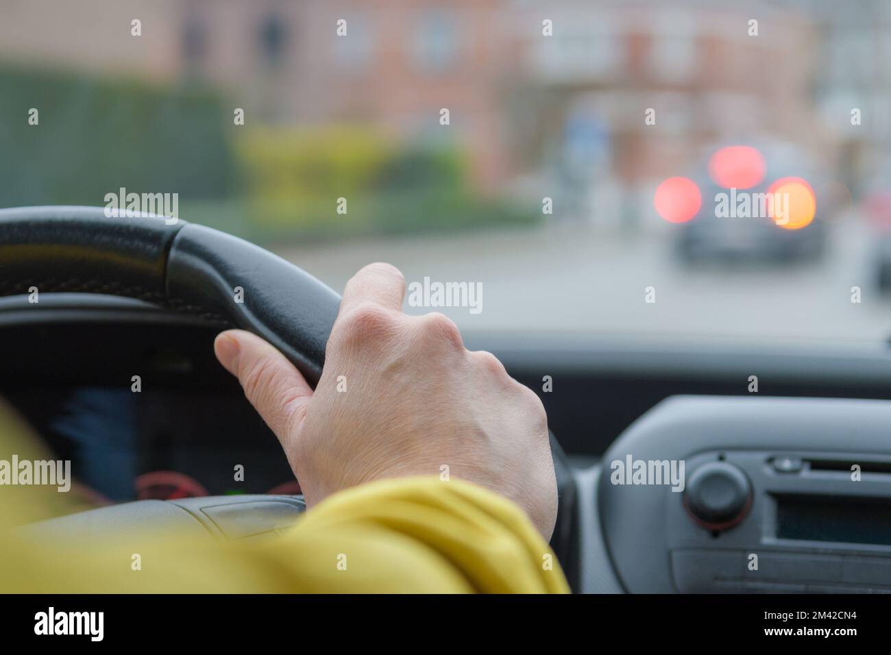 Freinage d'urgence en voiture. Pare-brise et perspective de la route. Direction. Mise au point sélectionnée. Main de femme sur un volant de voiture Banque D'Images