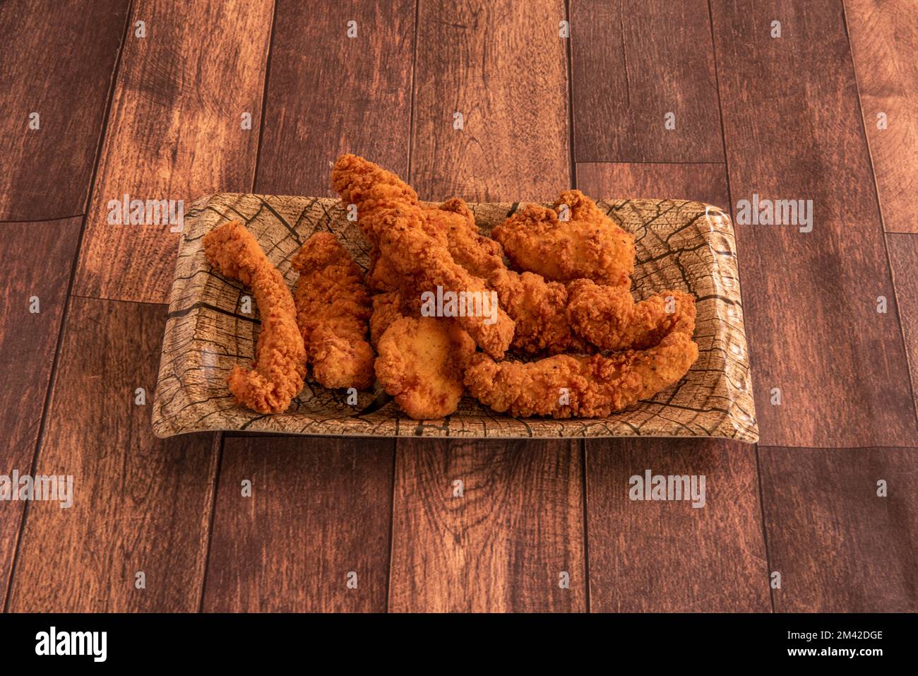 Plateau avec des doigts de poulet cuits et frits sur une table en bois Banque D'Images