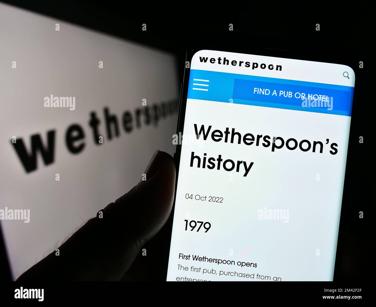 Personne tenant un téléphone portable avec le site Web de la société de pub britannique J D Wetherspoon plc à l'écran devant le logo. Concentrez-vous sur le centre de l'écran du téléphone. Banque D'Images