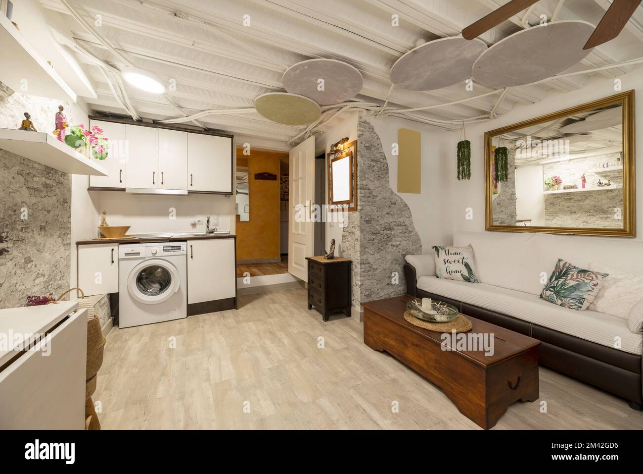 Ce studio comprend une kitchenette dans un coin et un salon avec un canapé deux tons et un grand miroir au cadre doré Banque D'Images