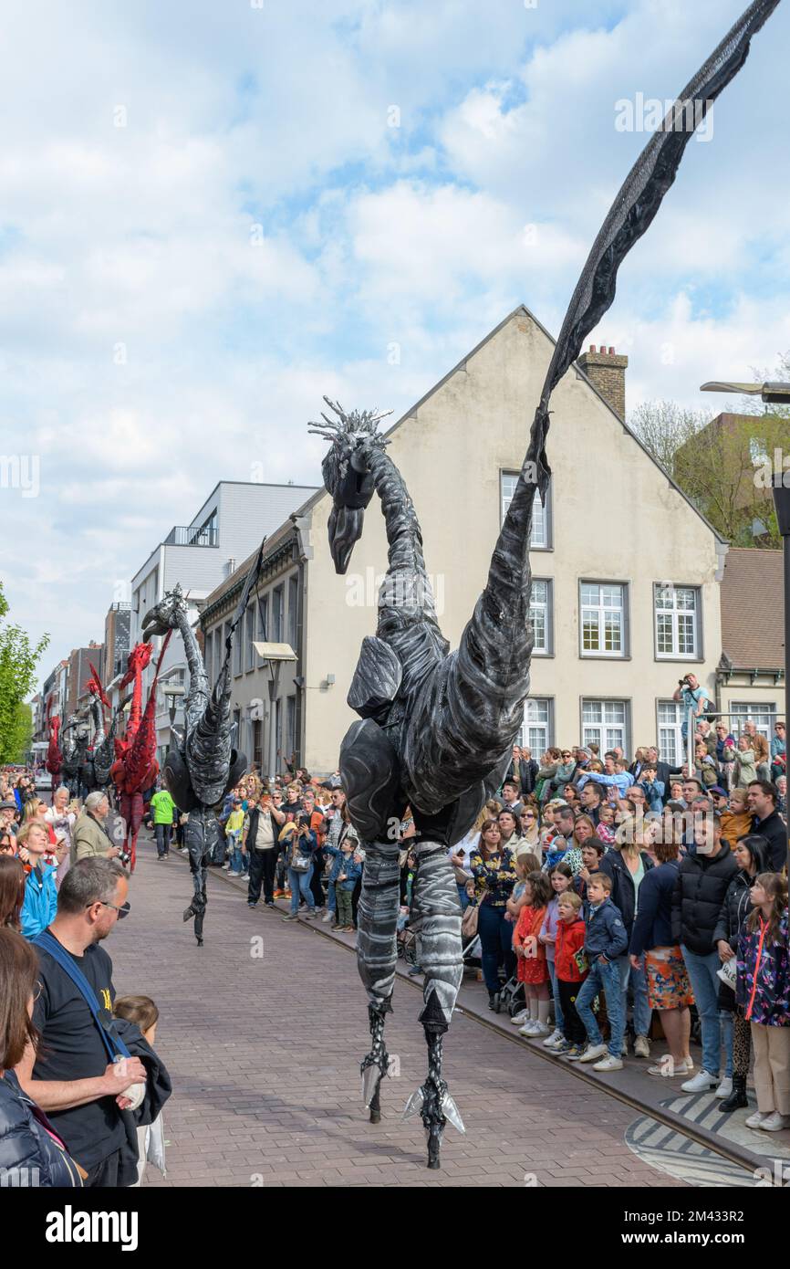 Genk. Limbourg - Belgique 01-05-2022. O-Parade en Belgique. Artistes en costumes de dinosaures sur pilotis dans une rue de ville. Banque D'Images
