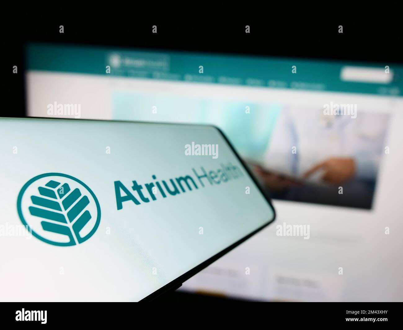 Téléphone mobile avec logo de l'entreprise hospitalière américaine Atrium Health à l'écran devant le site Web des entreprises. Mise au point à gauche de l'écran du téléphone. Banque D'Images