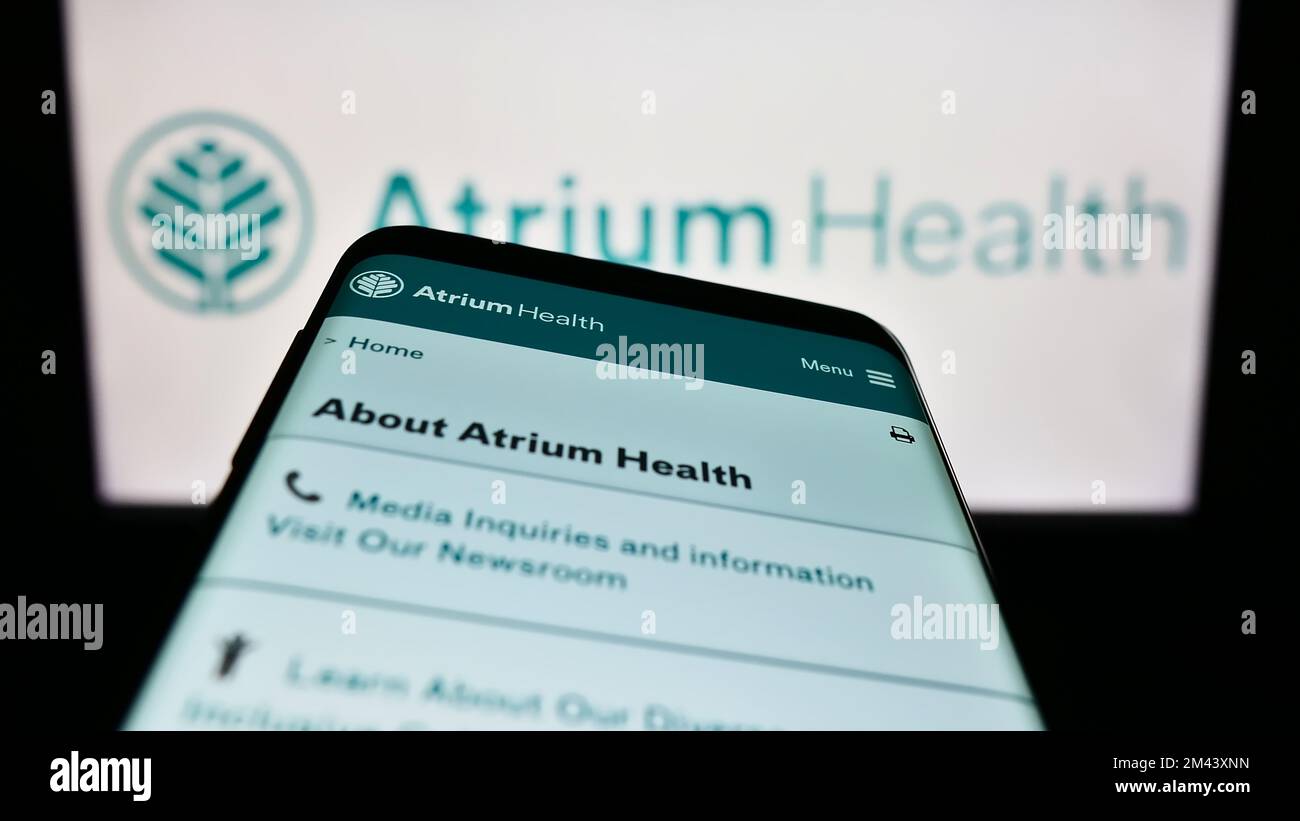Smartphone avec le site Web de l'entreprise hospitalière américaine Atrium Health à l'écran devant le logo de l'entreprise. Faites la mise au point dans le coin supérieur gauche de l'écran du téléphone. Banque D'Images