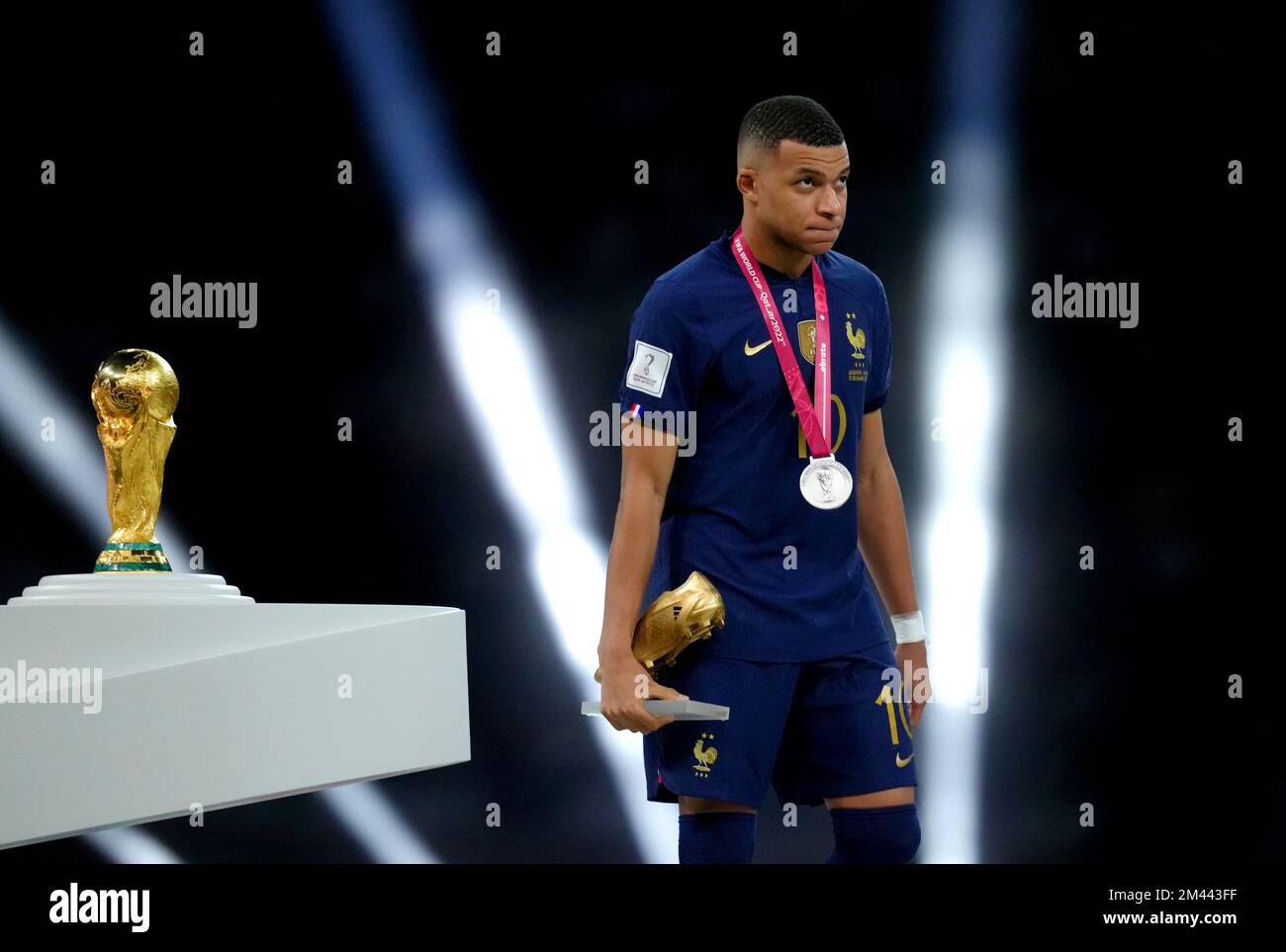 Kylian Mbappe, en France, passe devant le trophée de la coupe du monde de la FIFA après avoir reçu sa deuxième place après sa défaite lors de la finale de la coupe du monde de la FIFA au stade Lusail, au Qatar. Date de la photo: Dimanche 18 décembre 2022. Banque D'Images