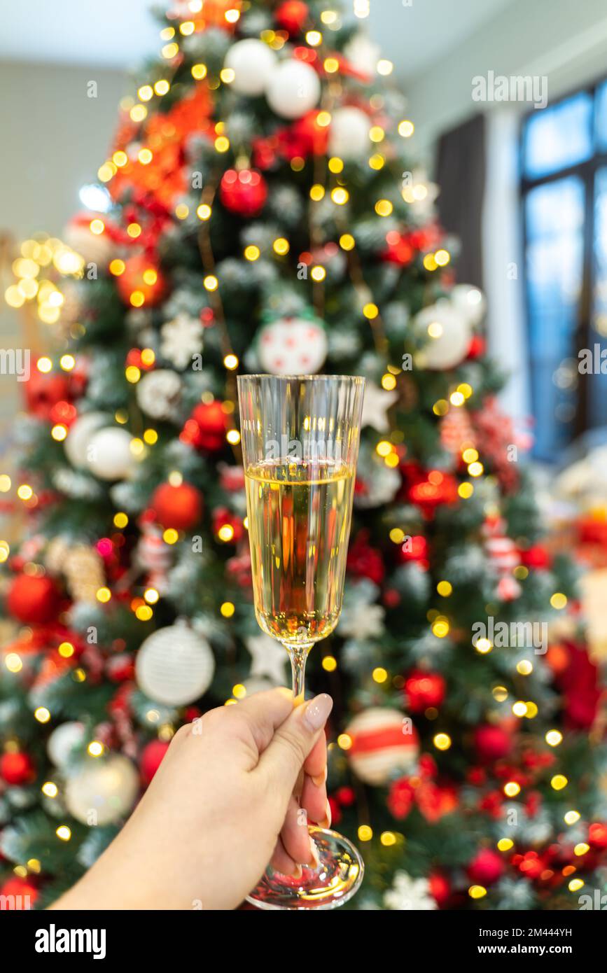 Champagne dans une main féminine sur fond de lumières d'arbre de Noël. Mise au point sélective. Jour de fête, moment d'ambiance Banque D'Images