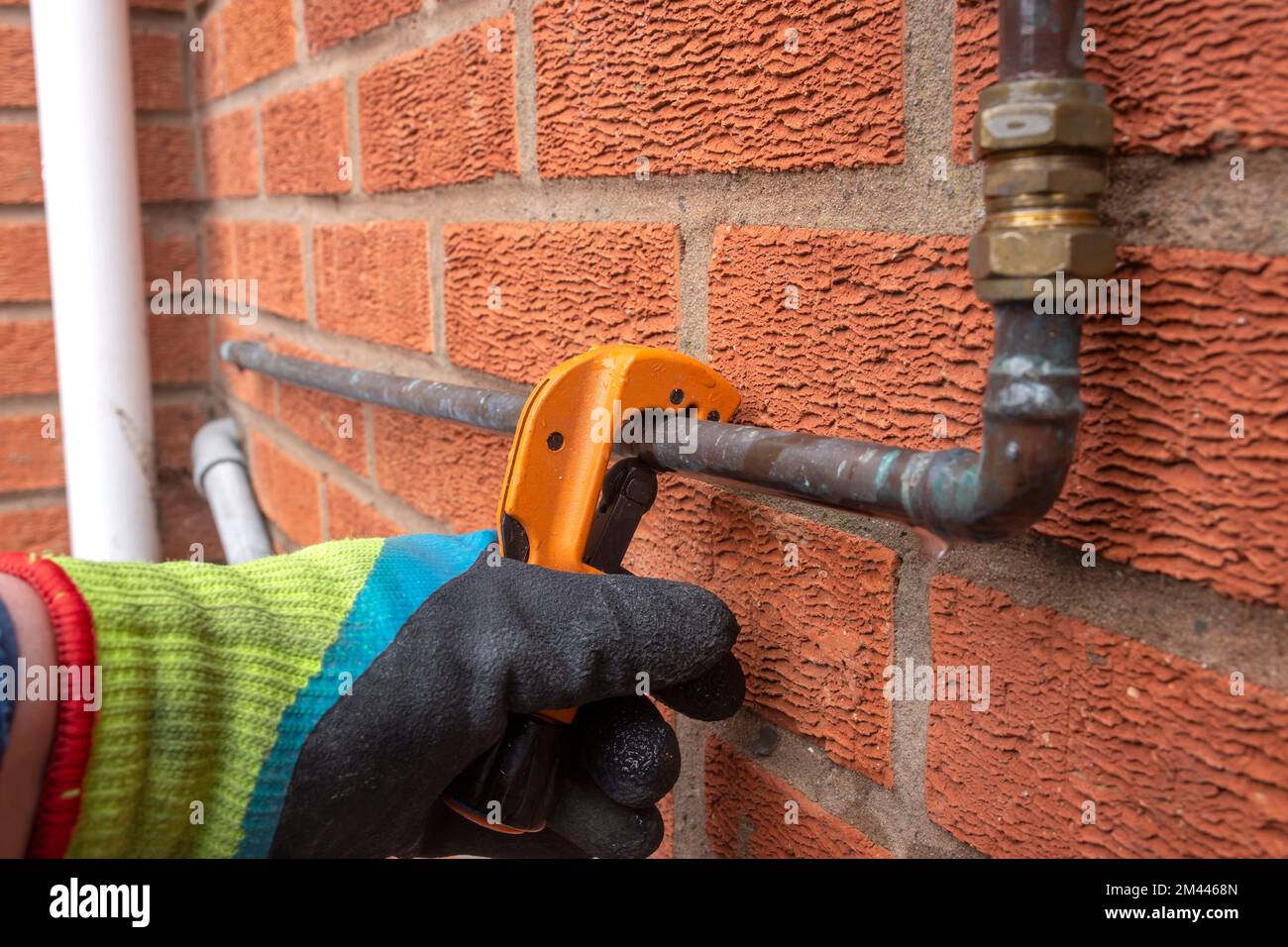 Homme coupant un tuyau d'eau en cuivre à l'aide d'un coupe-tube à  l'extérieur. Concept de plomberie Photo Stock - Alamy
