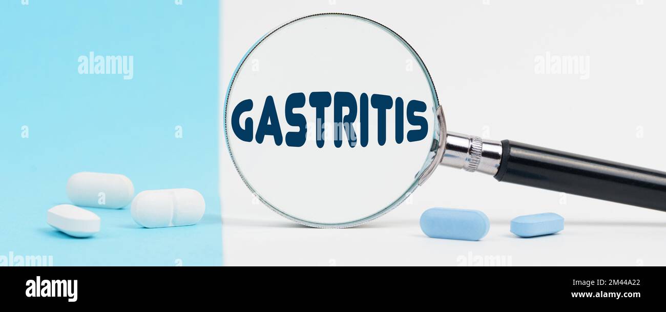 Médecine et concept de santé. Sur un fond bleu et blanc, il y a des pilules et une loupe, à l'intérieur de laquelle il est écrit - GASTRITE Banque D'Images Médecine et concept de santé. Sur un fond bleu et blanc, il y a des pilules et une loupe, à l'intérieur de laquelle il est écrit - GASTRITE Banque D'Images