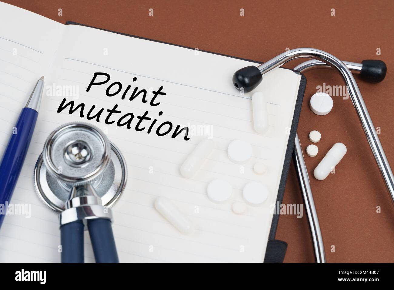 Médecine et concept de santé. Sur une surface brune se trouvent des pilules, un stylo, un stéthoscope et un carnet avec l'inscription - mutation ponctuelle Banque D'Images