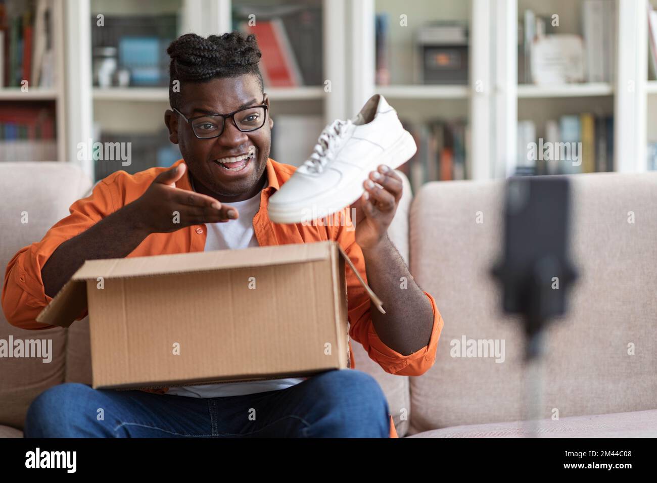 Un homme noir d'influence sur les médias sociaux examine les nouvelles chaussures Banque D'Images