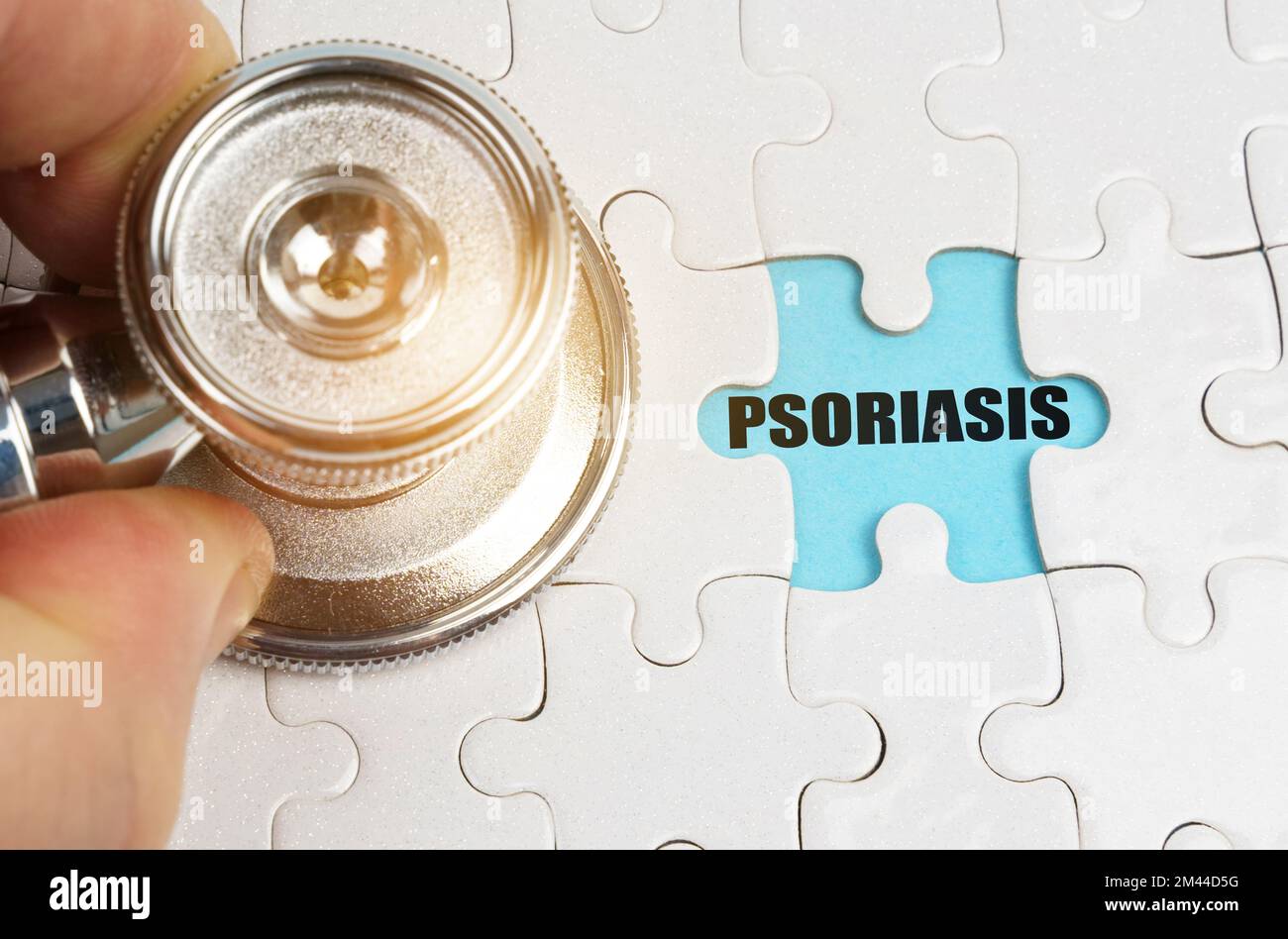 Concept médical. Sur les puzzles une main avec un stéthoscope, sur fond bleu l'inscription - PSORIASIS Banque D'Images Concept médical. Sur les puzzles une main avec un stéthoscope, sur fond bleu l'inscription - PSORIASIS Banque D'Images