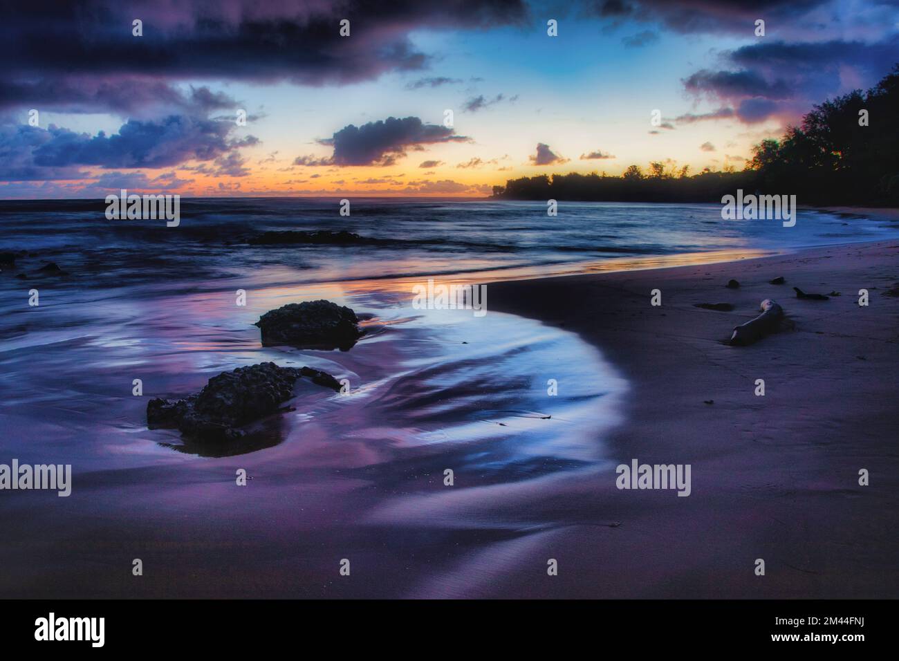 Le lever du soleil se reflète dans la marée à la baie d'Anohala sur la côte est de Kauai, Hawaï. Banque D'Images