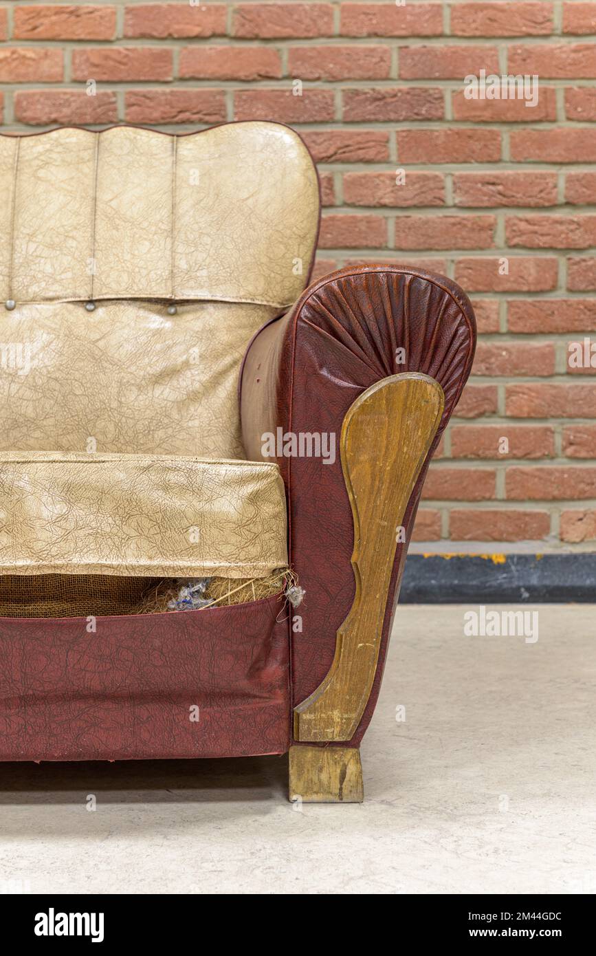 Ancien fauteuil vintage avec des traces de temps contre un mur de briques Banque D'Images