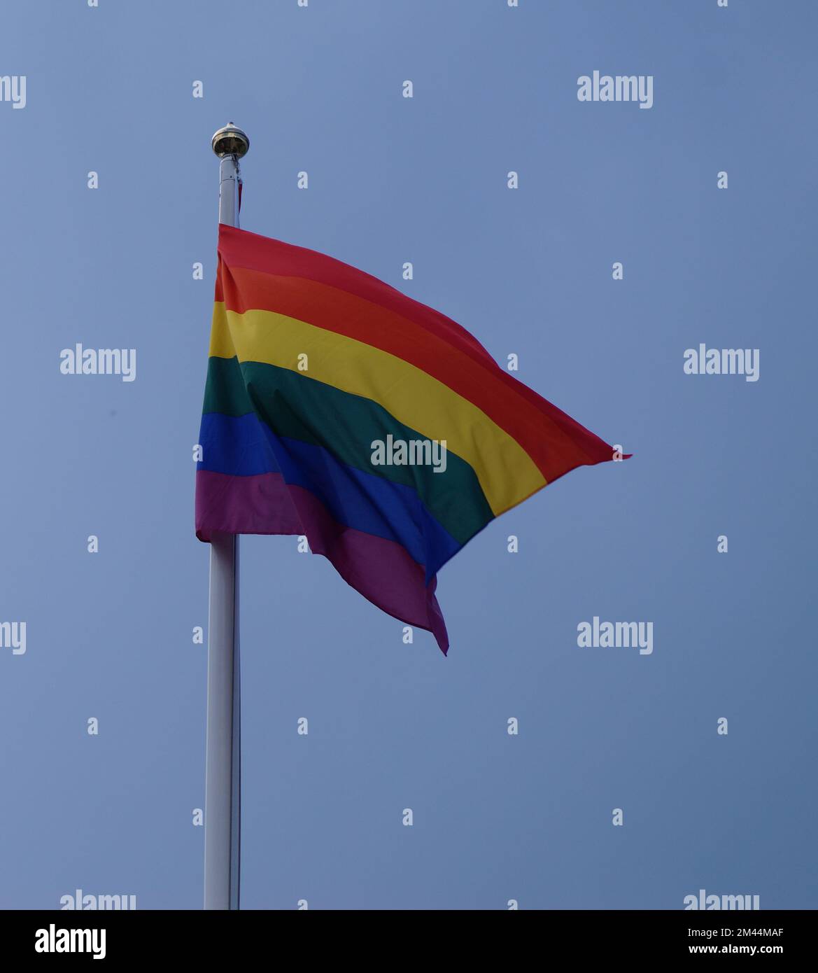 Vue à angle bas du drapeau arc-en-ciel contre le ciel bleu clair Banque D'Images