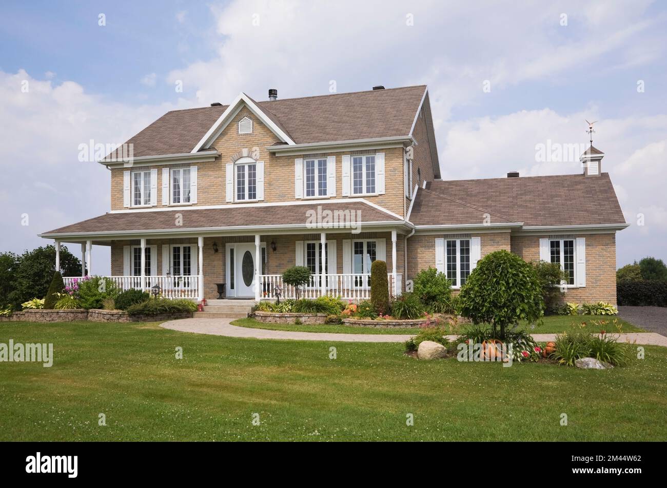 Brique nuancée beige et tan avec garniture blanche maison de style cottage en été. Banque D'Images