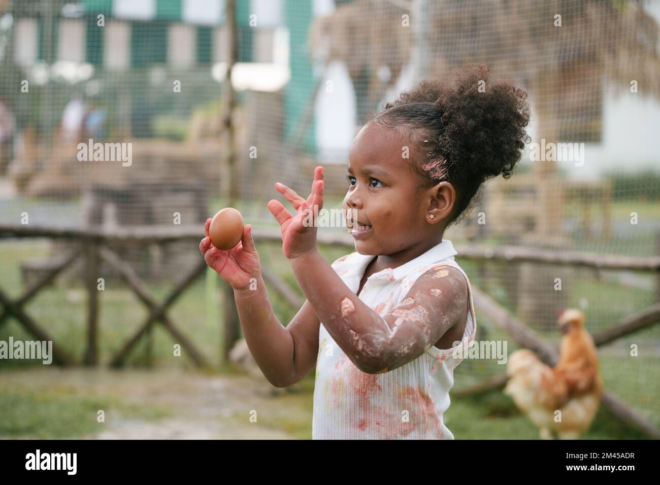 Enfant afro-américain tenant un œuf de poulet avec une coloration de couleur sur la main et la robe. Banque D'Images