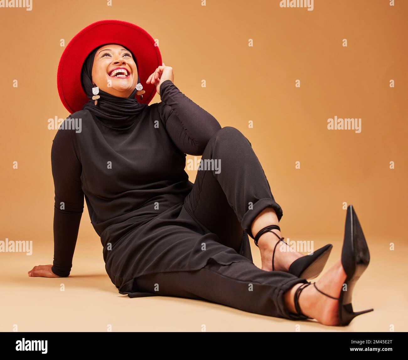 Musulmane, femme heureuse et riant sur fond de studio avec la mode, chapeau tendance et style de luxe. Sourire, bonheur et modèle islamique mûr avec beauté Banque D'Images