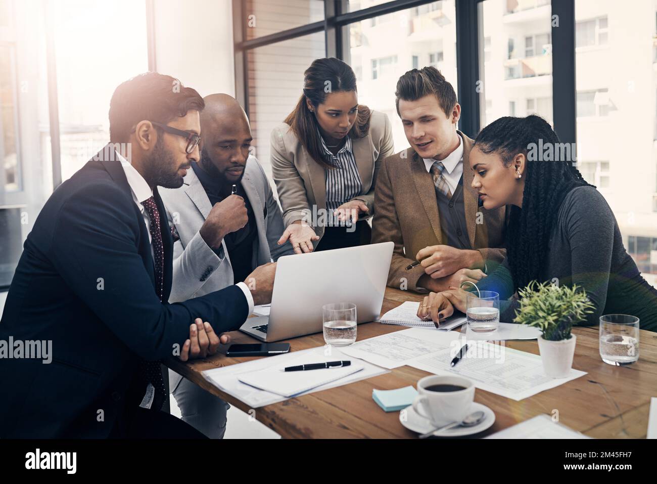 La technologie et le travail d'équipe vous permettent d'y parvenir plus rapidement. un groupe de jeunes hommes d'affaires utilisant un ordinateur portable lors d'une réunion dans un bureau moderne. Banque D'Images