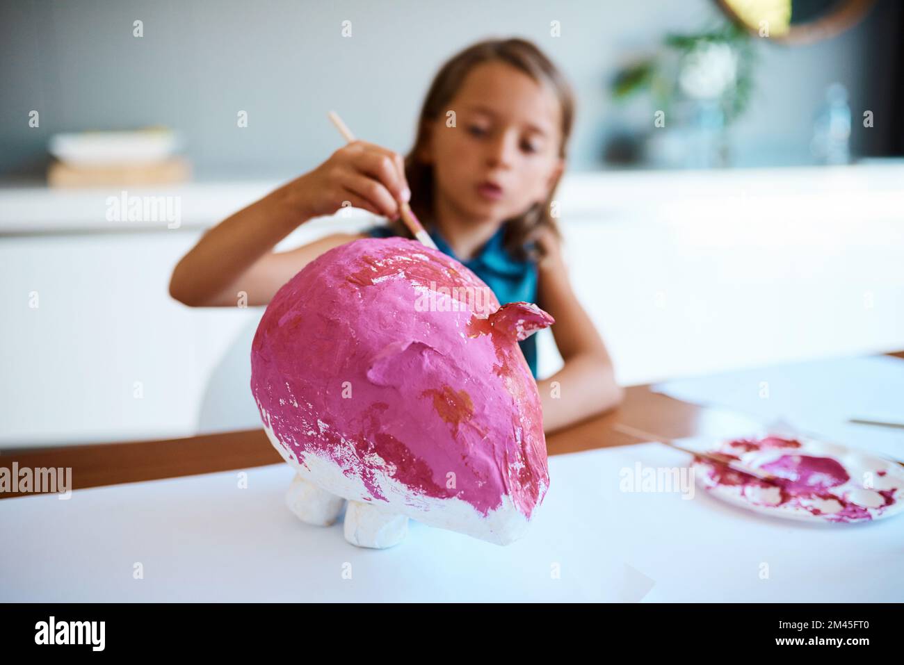 Délice de porc. une adorable petite fille travaillant sur son projet d'art à la maison. Banque D'Images