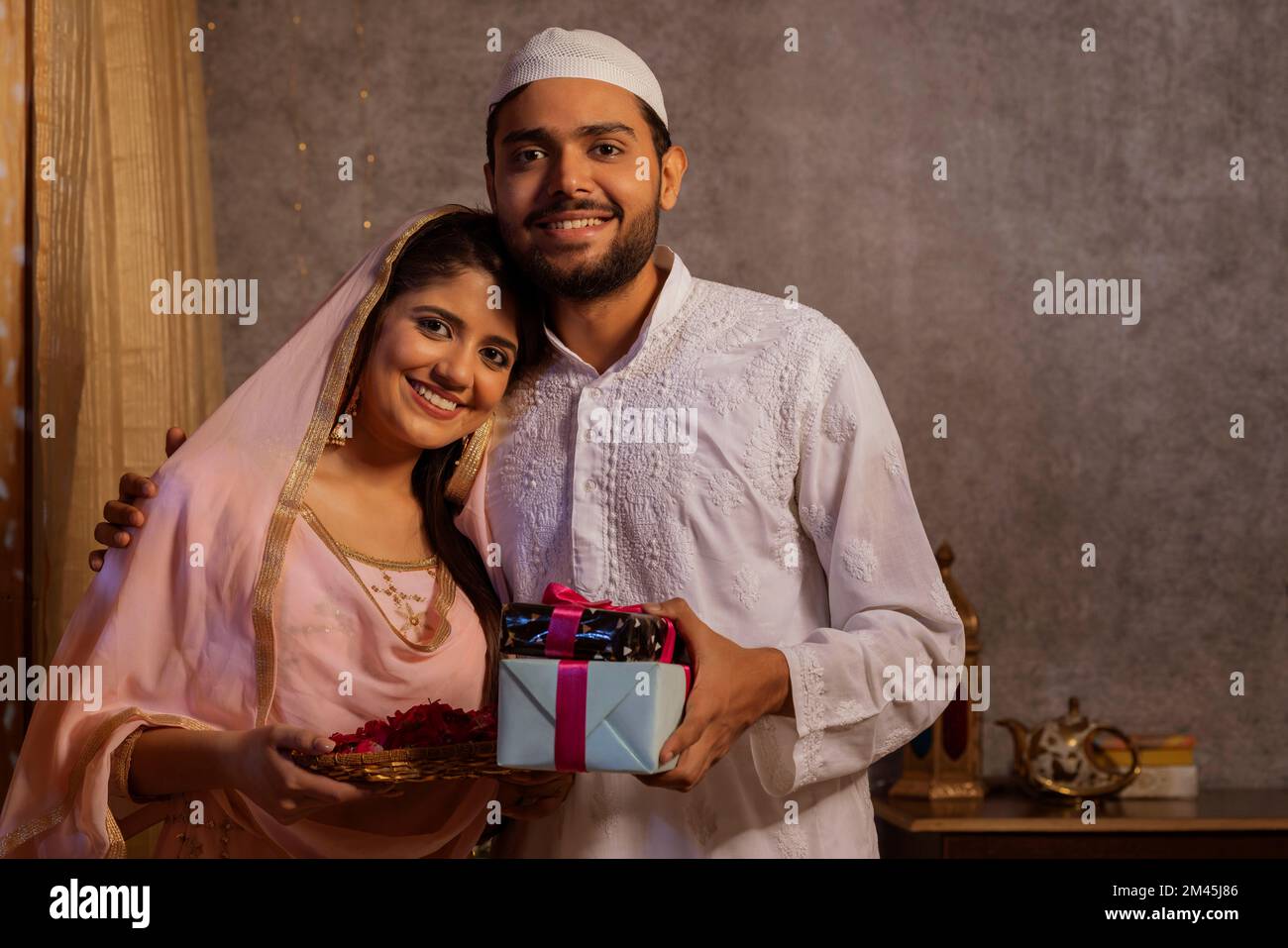 Portrait d'un couple musulman heureux avec cadeau et pétales de rose pendant Eid-UL-Fitr Banque D'Images