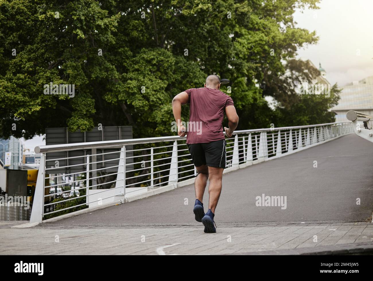 Fitness, course à pied et homme sur un pont pour l'entraînement, le bien-être et le cardio dans une ville, cardio et énergie. Sport, coureur et exercice masculin sur une route pour Banque D'Images