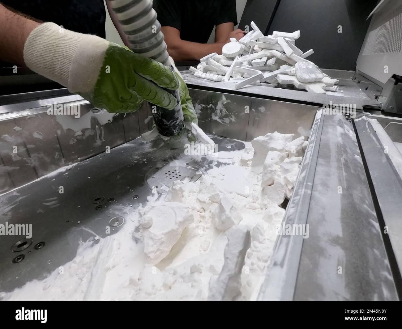 Extraction de modèles de poudre de polyamide blanc dans la chambre de  travail de l'imprimante 3D, nettoyage et élimination de la poudre.  Processus de création de modèle sur imprimante poudre 3D. Multi