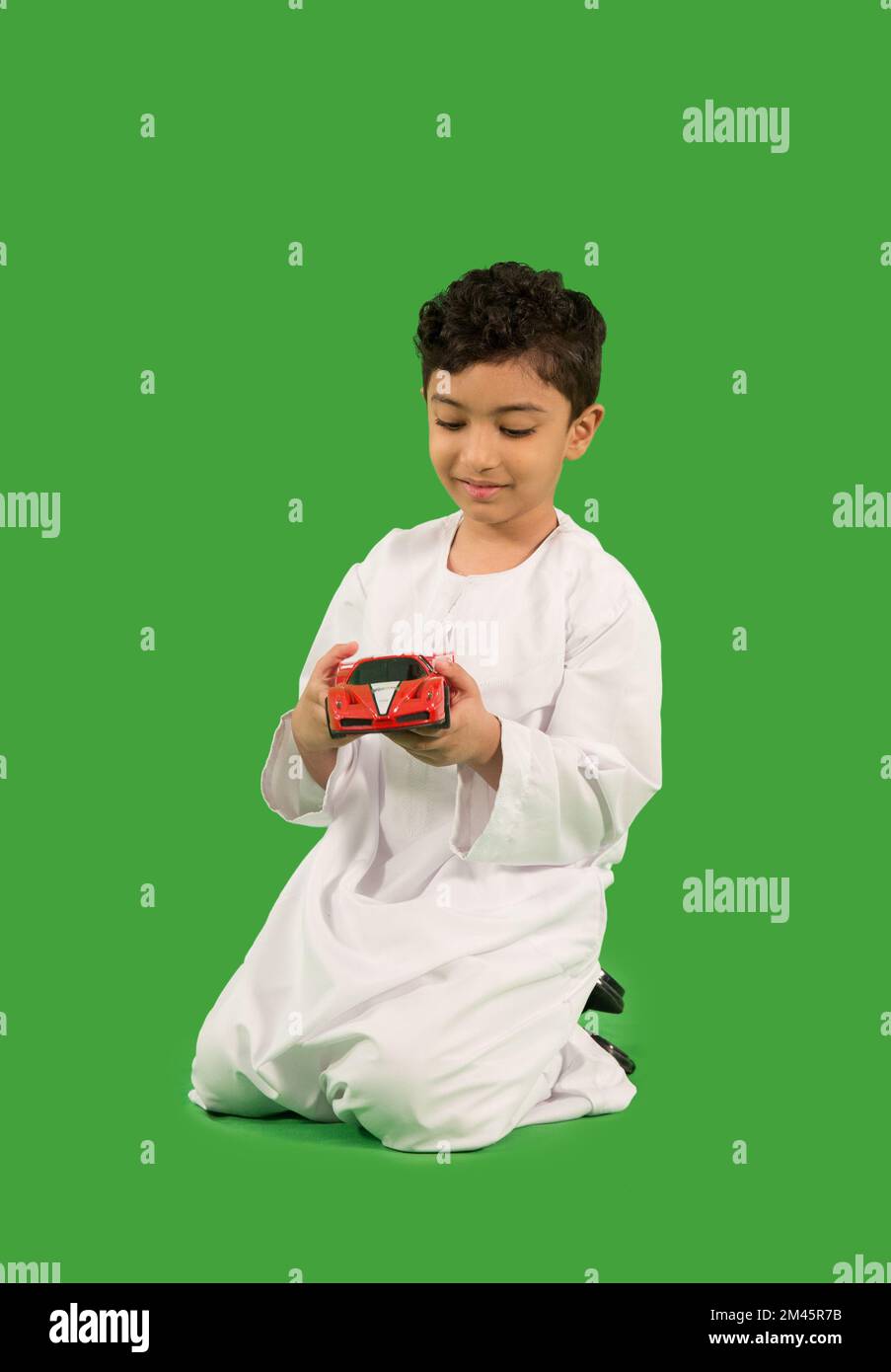 Garçon arabe poussant voiture jouet. Banque D'Images