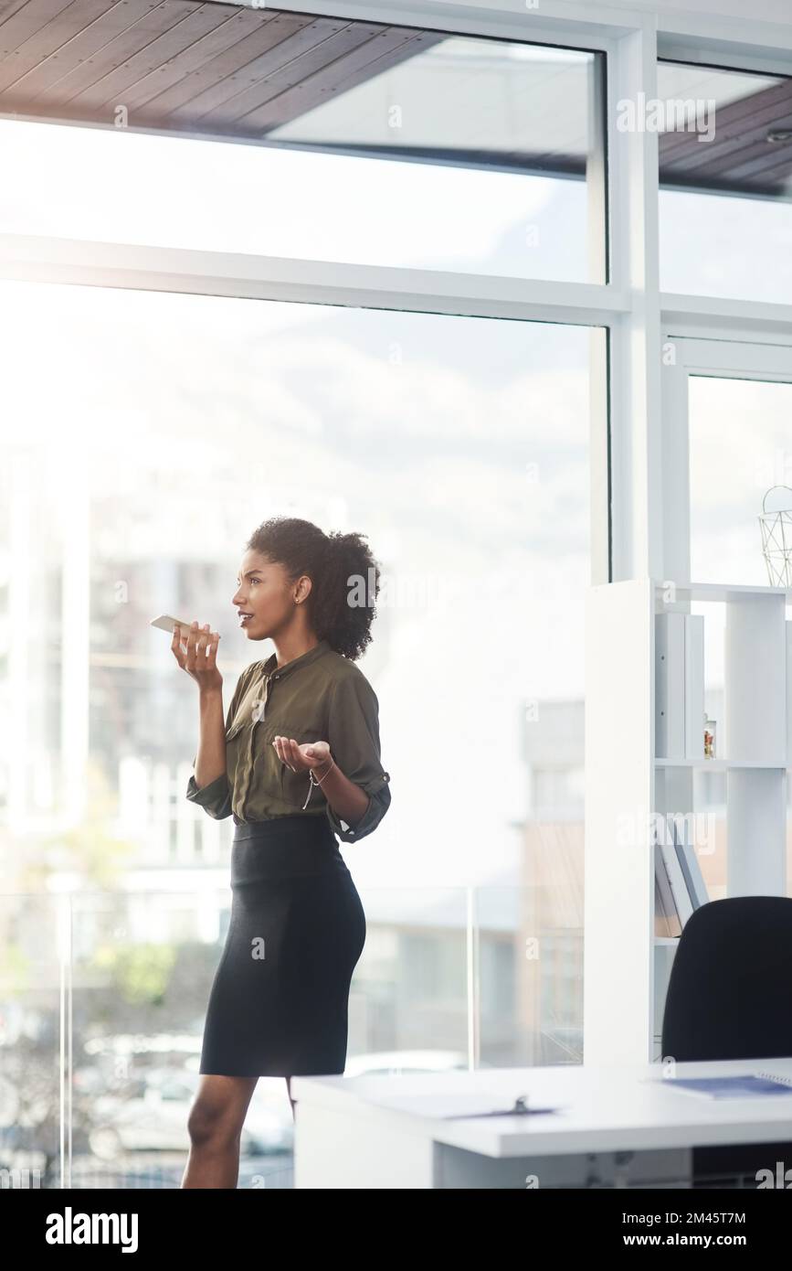 Les femmes intelligentes et les smartphones se méritent. une jeune femme d'affaires debout dans son bureau et occupée à parler sur un smartphone. Banque D'Images