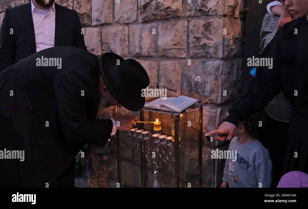 JÉRUSALEM, ISRAËL - DÉCEMBRE 18 : le rabbin Yitzchak Goldstein, chef de la Diaspora Yeshiva allume une bougie avec sa famille, à l'extérieur de leur maison la première nuit de la fête juive de Hanukkah, parfois appelée fête des lumières, sur 18 décembre 2022 à Jérusalem, Israël. Les Juifs du monde entier célèbrent aujourd'hui le premier jour de Hanukkah, le festival juif de huit jours. Hanoukkah, ou Chanukah, commémore la victoire juive en 165 avant J.-C. sur l'oppression syro-grecque menée par le roi Antiochus IV Crédit : Eddie Gerald/Alay Live News Banque D'Images