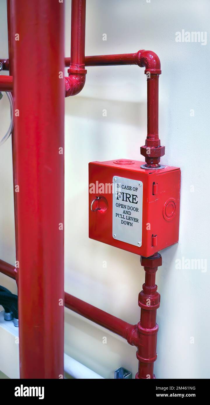 Boîte métallique rouge et installation verticale tube rouge du système de prévention des incendies avec fond de mur en béton dans le bâtiment Banque D'Images