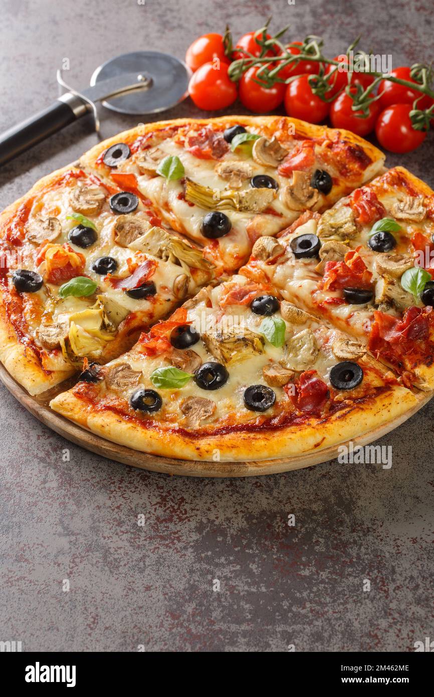 Capricciosa une pizza classique avec des artichauts, des olives, du jambon et des champignons à proximité sur le panneau de bois sur la table. Verticale Banque D'Images