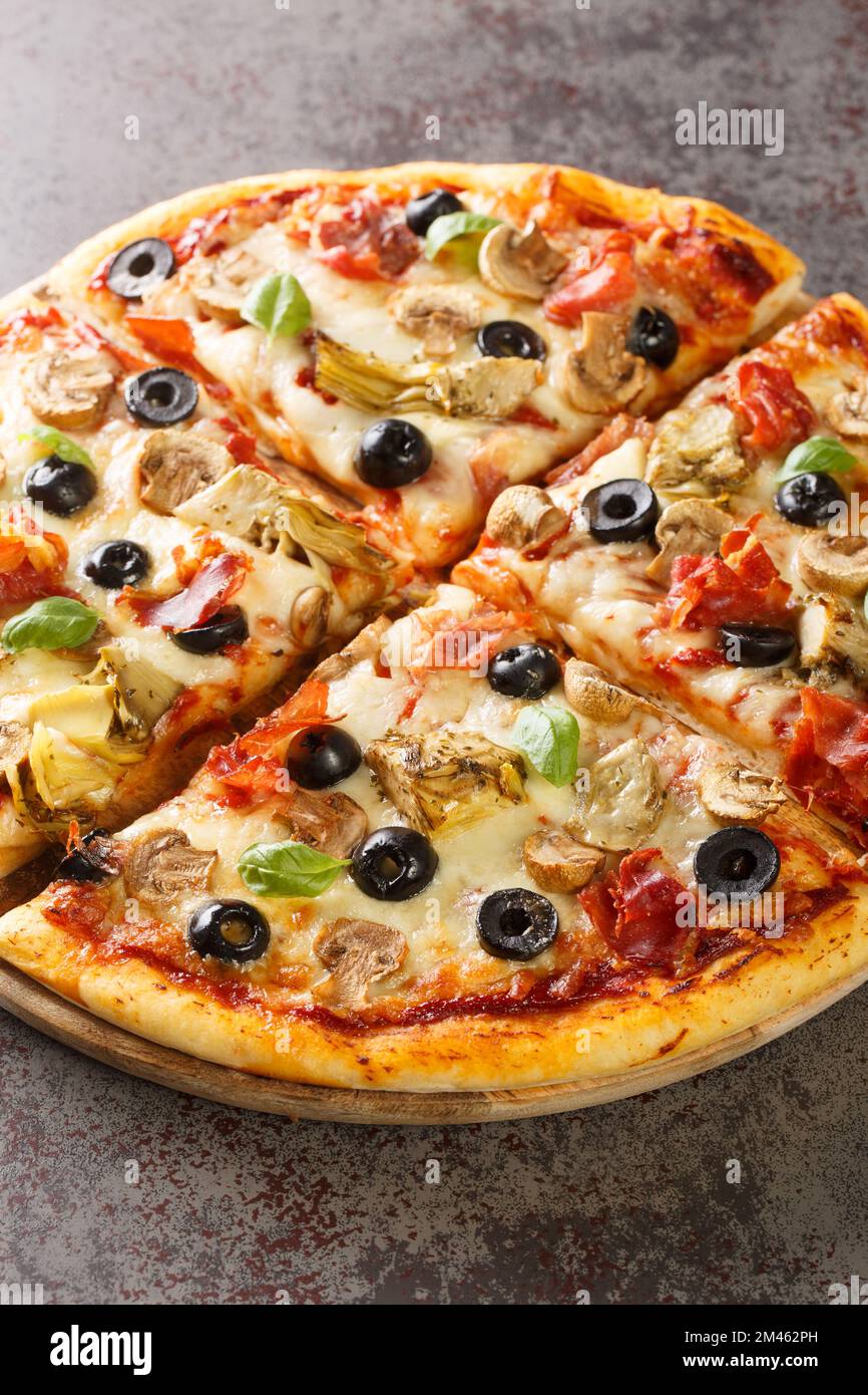 Pizza capricciosa aux champignons blancs, jambon, artichaut, tomates, olives, parmesan et mozzarella sur bois sur la table. Verticale Banque D'Images