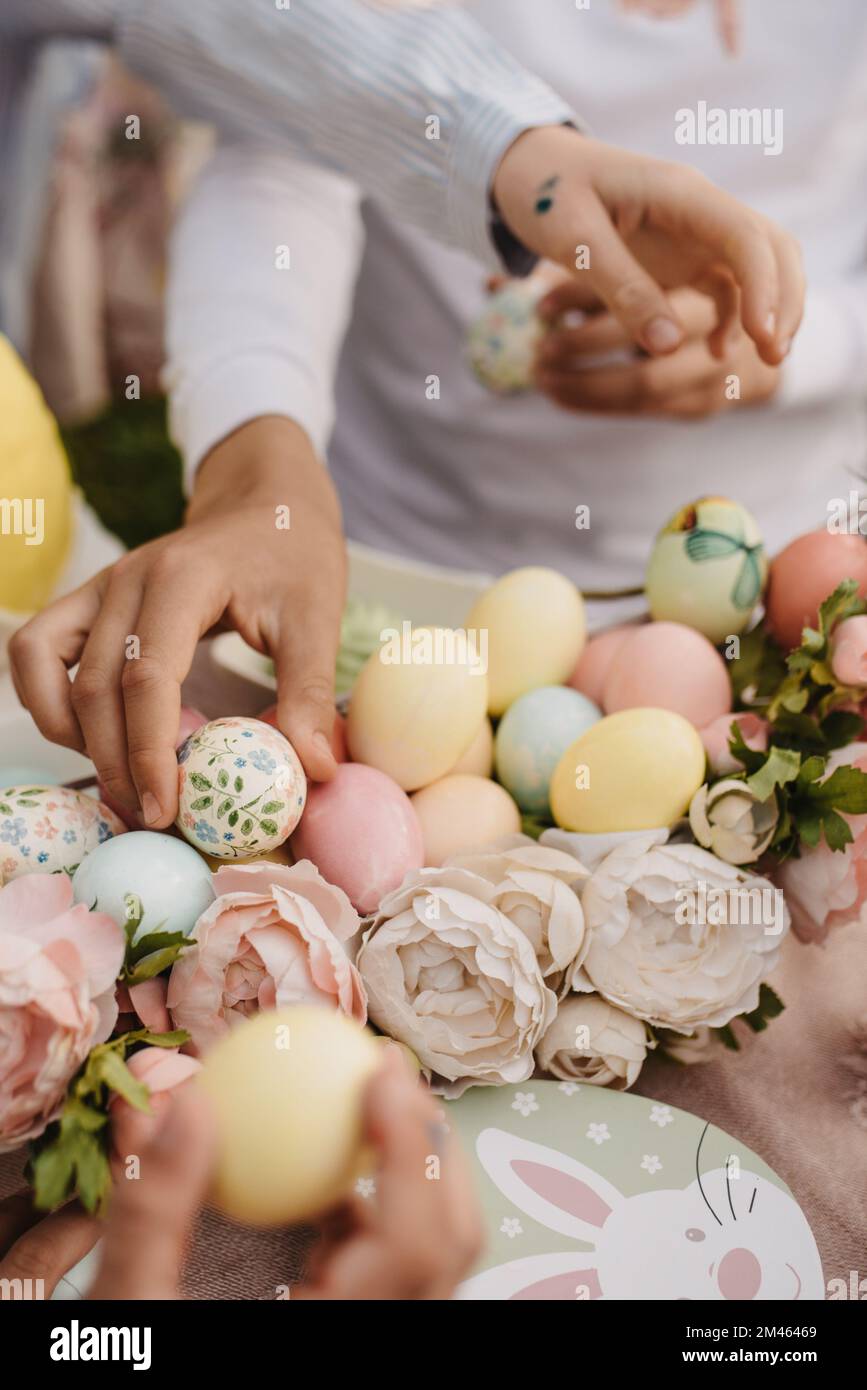 Un cliché vertical de personnes jouant avec les oeufs de Pâques colorés sur le fond flou Banque D'Images