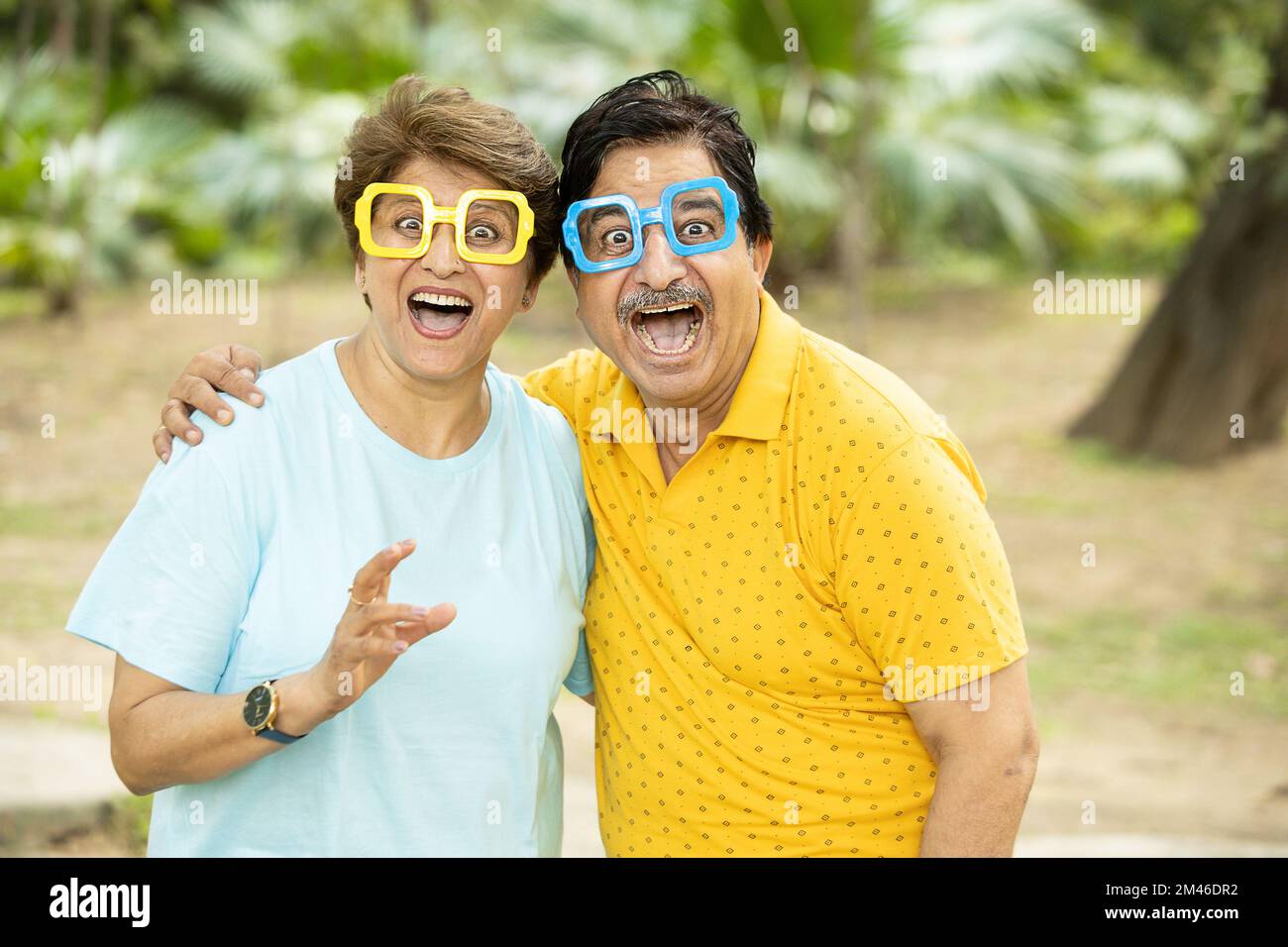 Portrait d'un couple indien fou et amusant, portant des lunettes funky à l'extérieur du parc. Des personnes matures faisant des visages. Banque D'Images