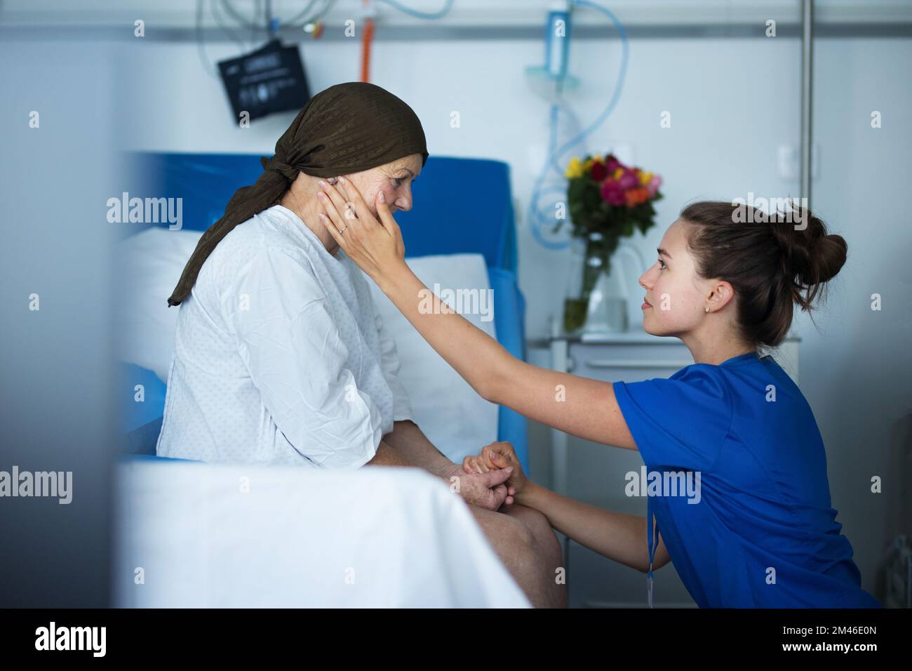 Infirmière empathique prenant soin de la femme âgée avec le cancer, en traquant sa joue. Banque D'Images