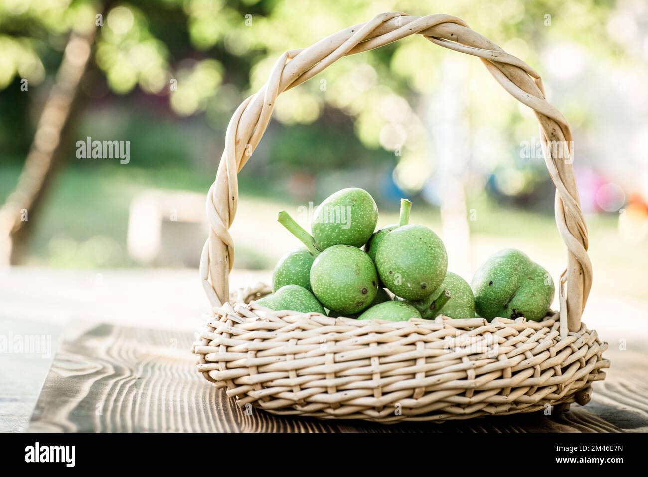 Noix vertes dans un panier en osier. Collection d'ingrédients pour des aliments sains. Ancienne table vintage et fruits de noyer entiers non mûrs. Banque D'Images