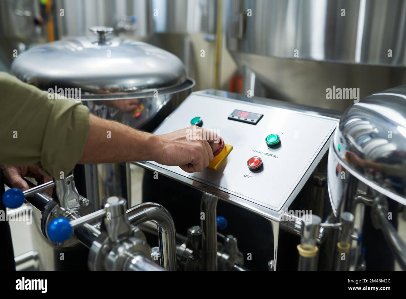 Image de gros plan du travailleur qui lance l'équipement de brasserie pour la fermentation et la maturation de la bière Banque D'Images