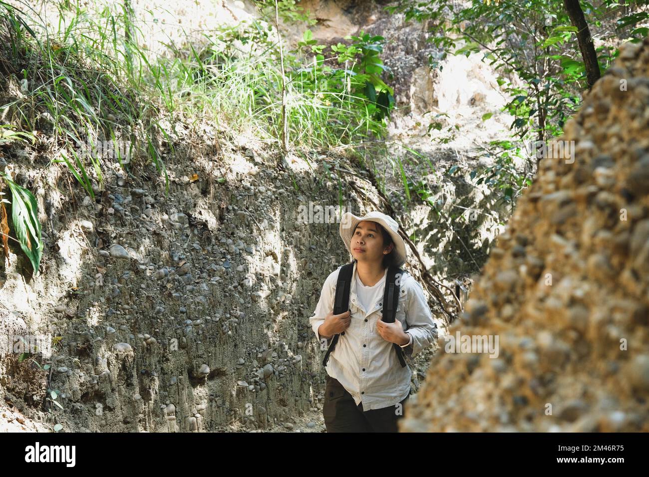 Femme géologue avec sac à dos explorant le sentier de la nature en forêt et analysant le rocher ou le gravier. Les chercheurs recueillent des échantillons de matériel biologique. Env Banque D'Images