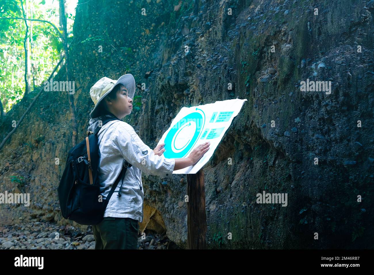 Femme géologue utilisant une carte avec des icônes, examinant un chemin naturel et analysant des roches ou du gravier. Les chercheurs recueillent des échantillons de matériel biologique. FR Banque D'Images